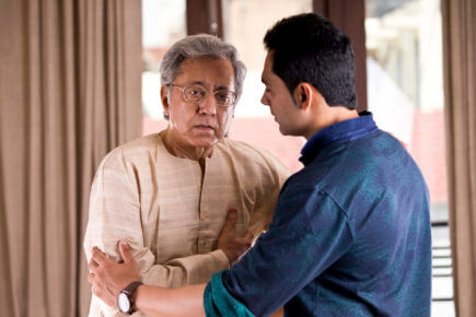 Son supporting father suffering with chest pain at home